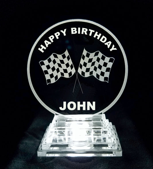 acrylic round cake topper designed with a pair of racing flags, Happy Birthday and a name