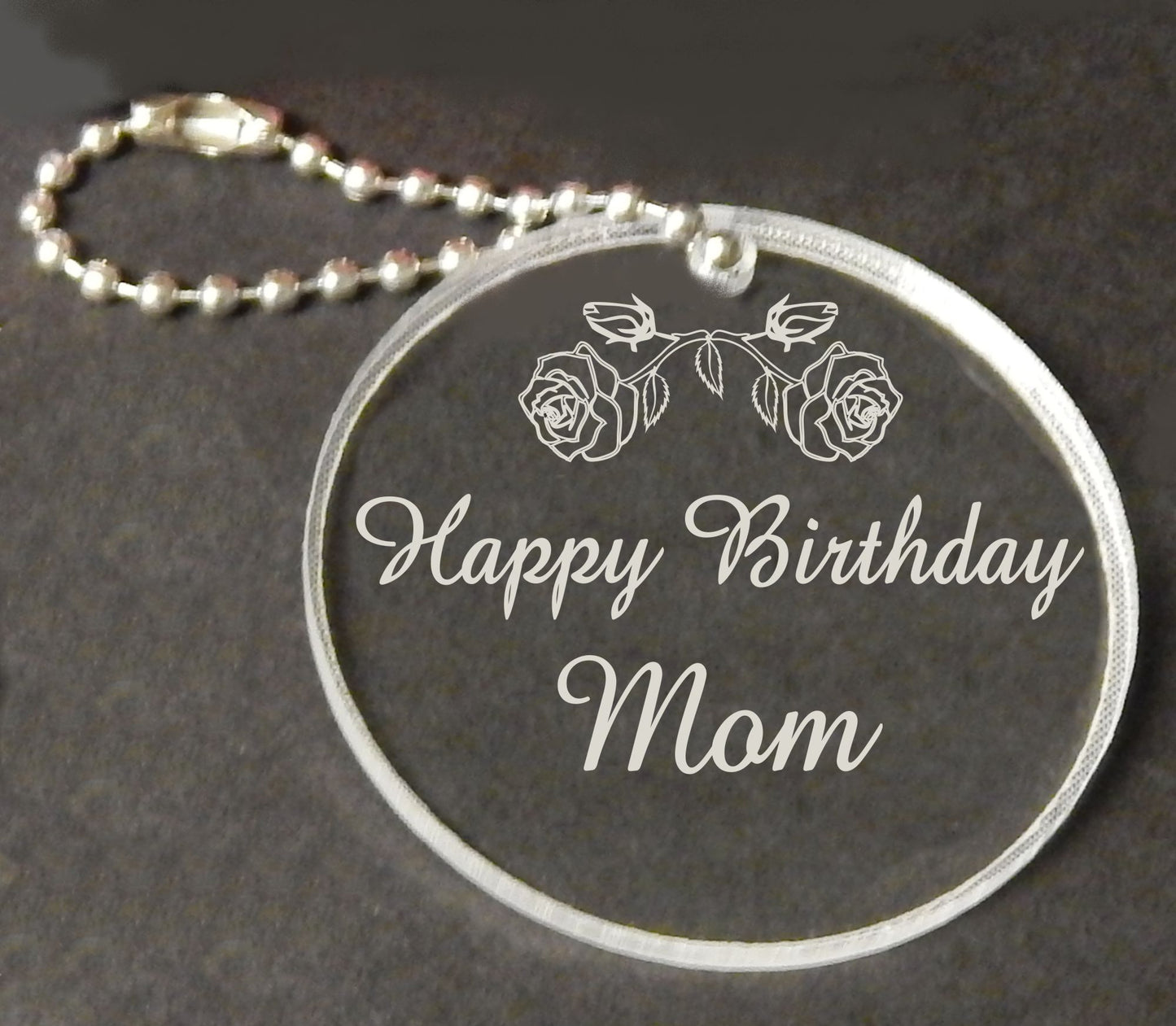 acrylic round keychain favor engraved with a rose design and attached to a small chain