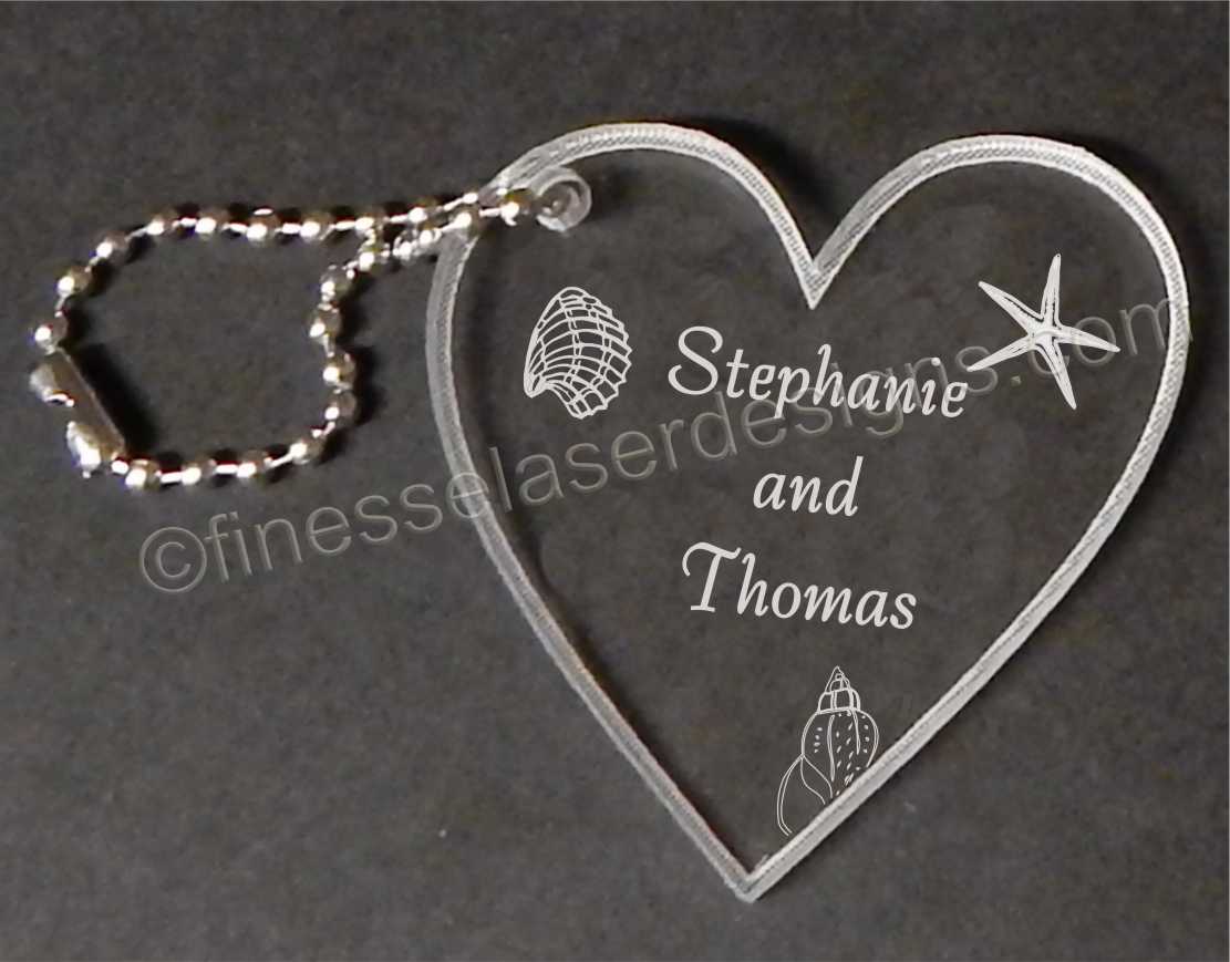 heart shaped key chain engraved with seashells and names and a small metal chain attached