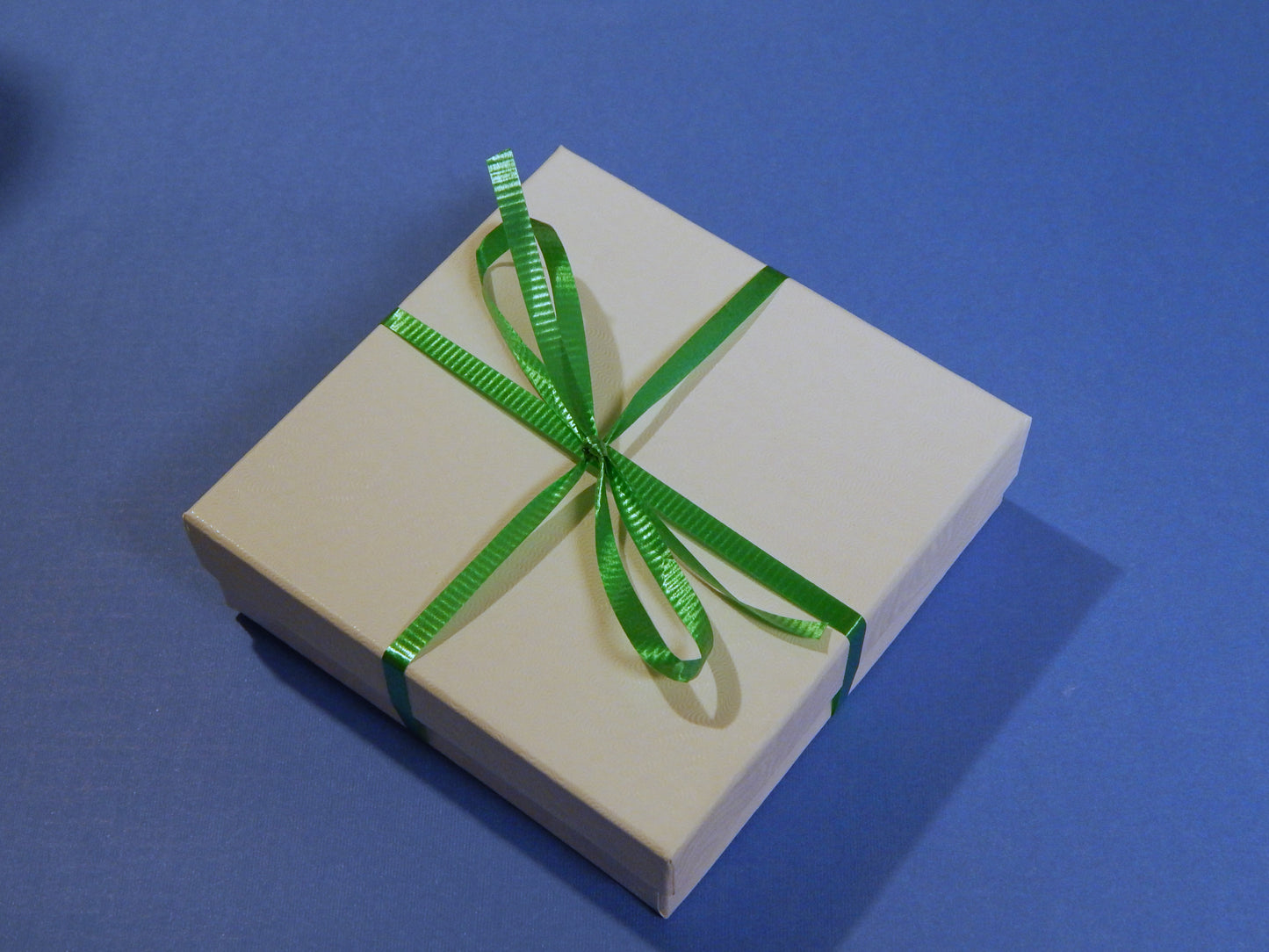 white gift box shown with green ribbon tied in a bow