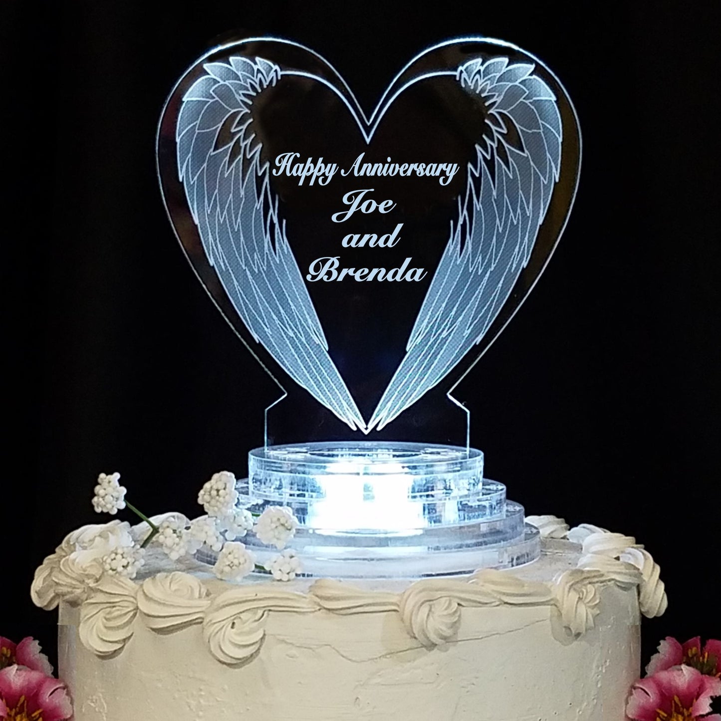 heart shaped acrylic cake topper designed with a downward angel wings design along with Happy Anniversary and names