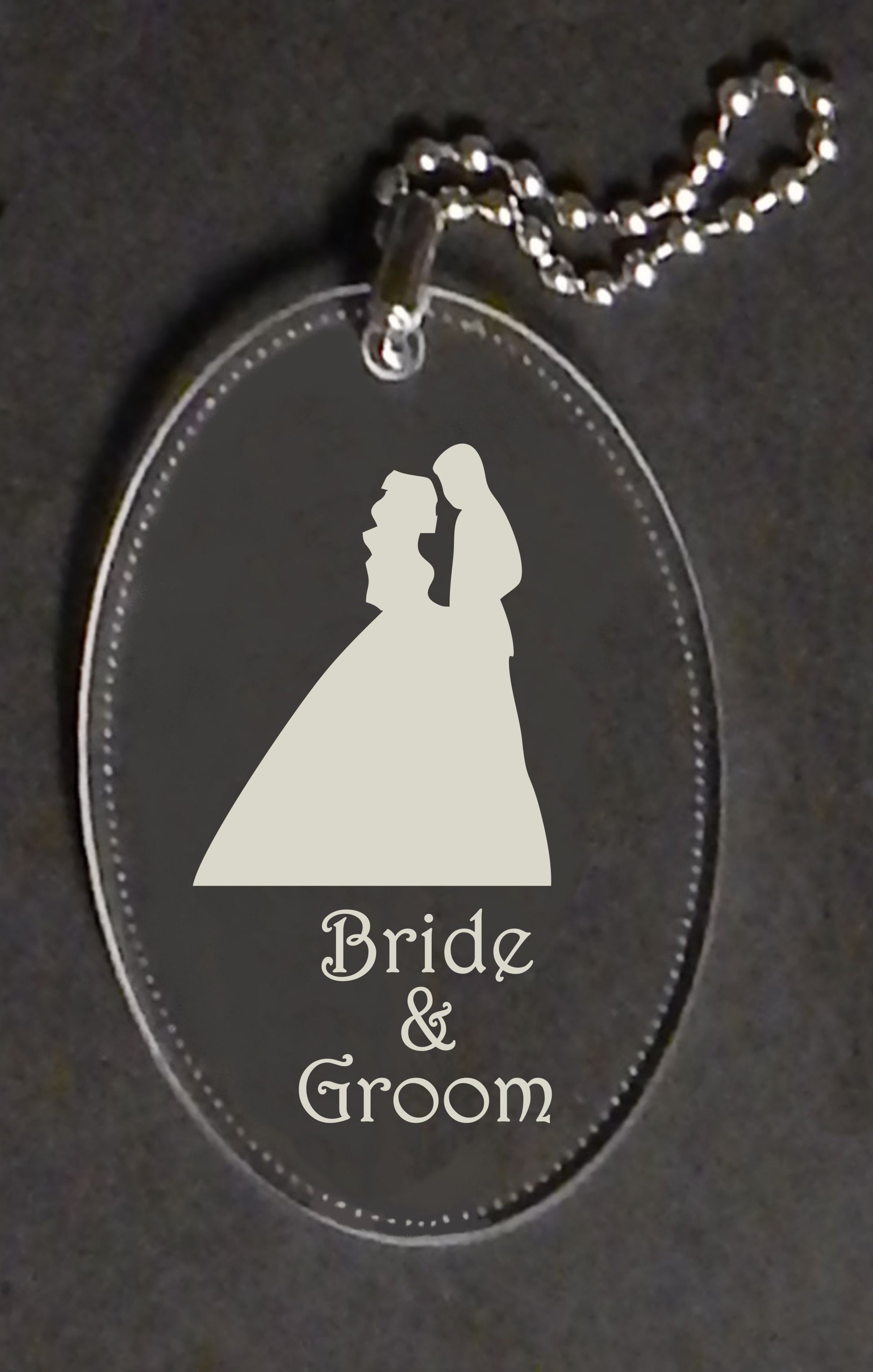 oval keychain designed with a silhouette of man and woman, along with bride and groom names, attached to a small metal chain
