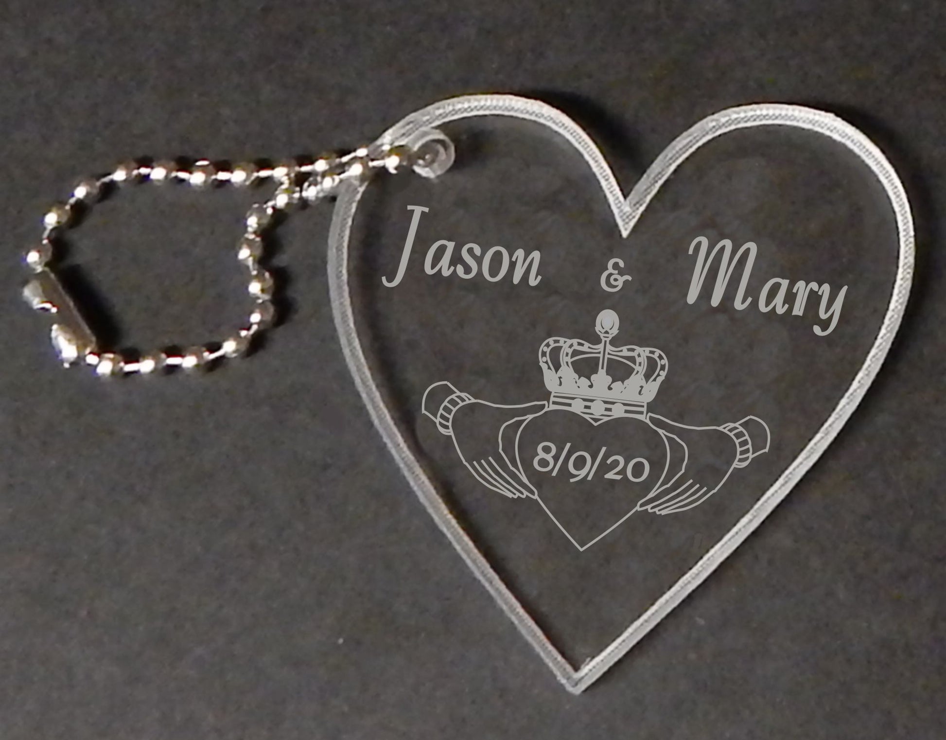 heart shaped acrylic keychain designed with a claddagh along with names and date, with a small metal chain attached
