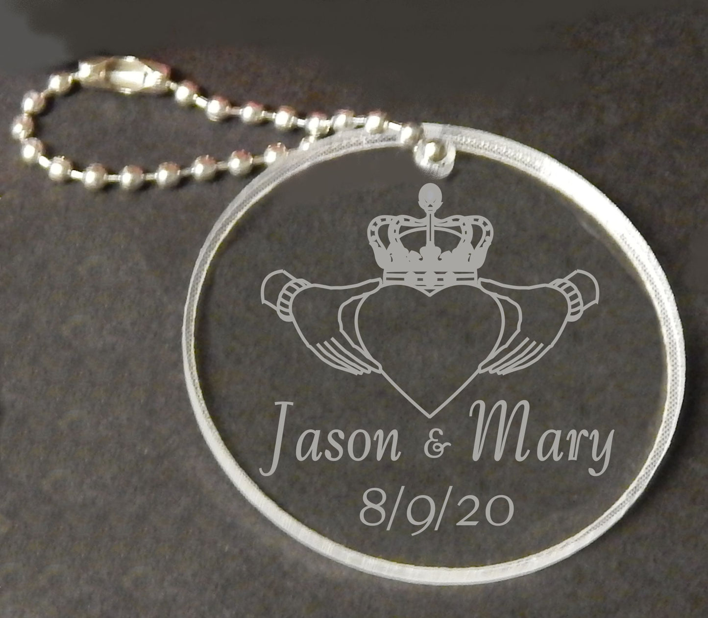 round acrylic keychain designed with a claddagh symbol and names and date, attached to a small metal chain