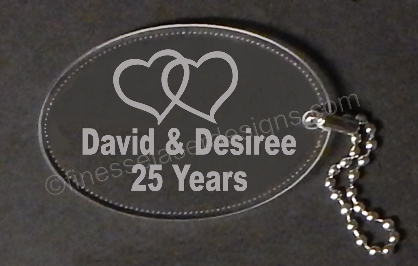 clear acrylic oval keychain with a double heart design along with names and number of anniversary years, with a small chain attached