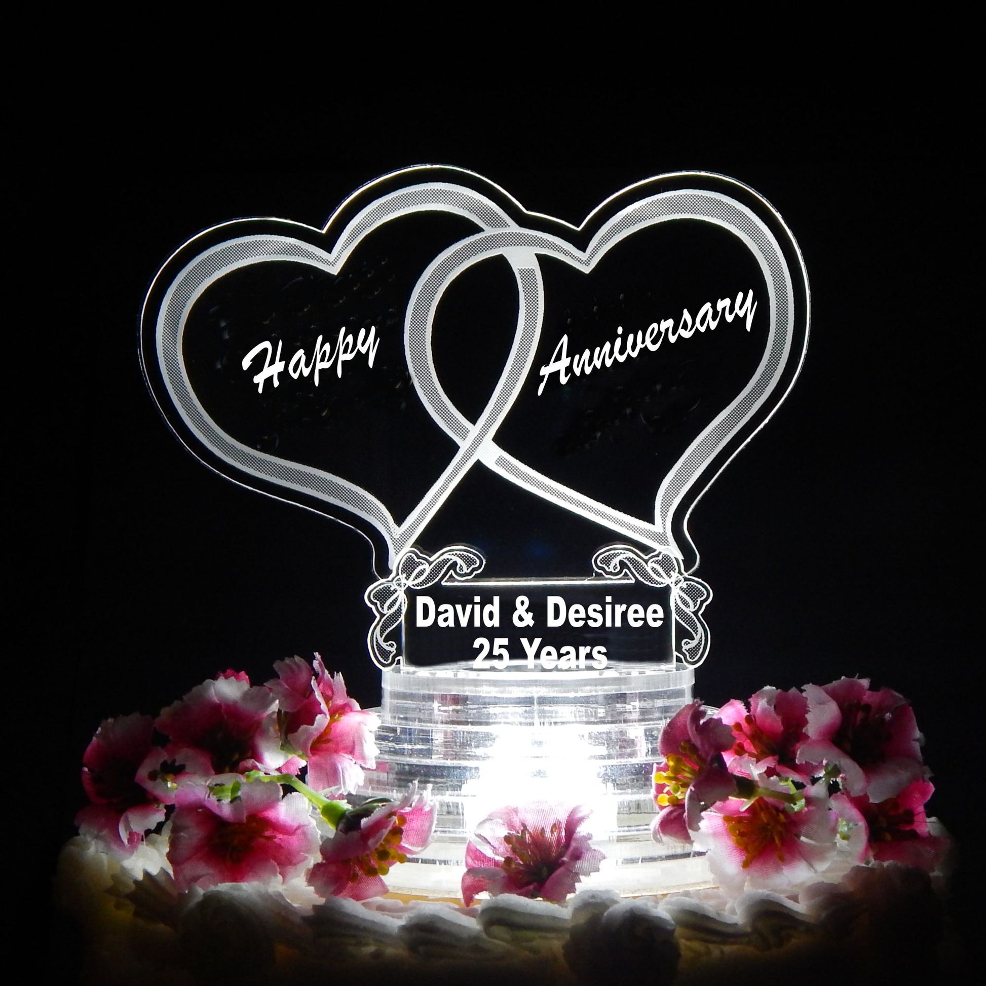 clear acrylic cake topper designed with two hearts with Happy Anniversary engraved inside the hearts, along with names and number of years for anniversary