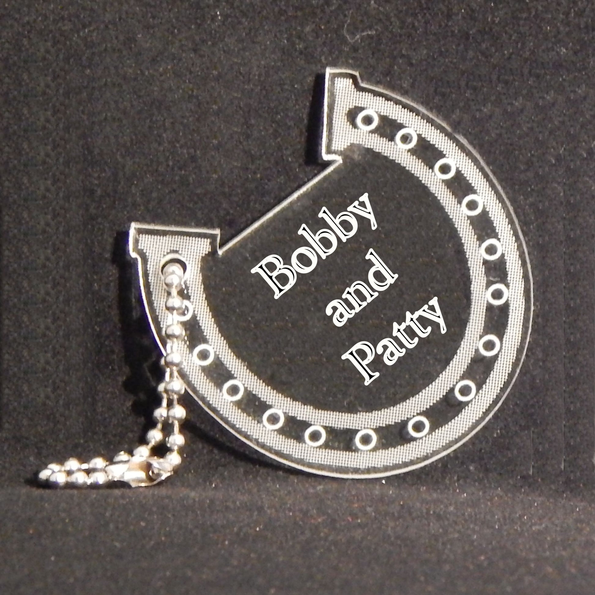 horseshoe shaped keychain engraved with names and attached to a small metal chain
