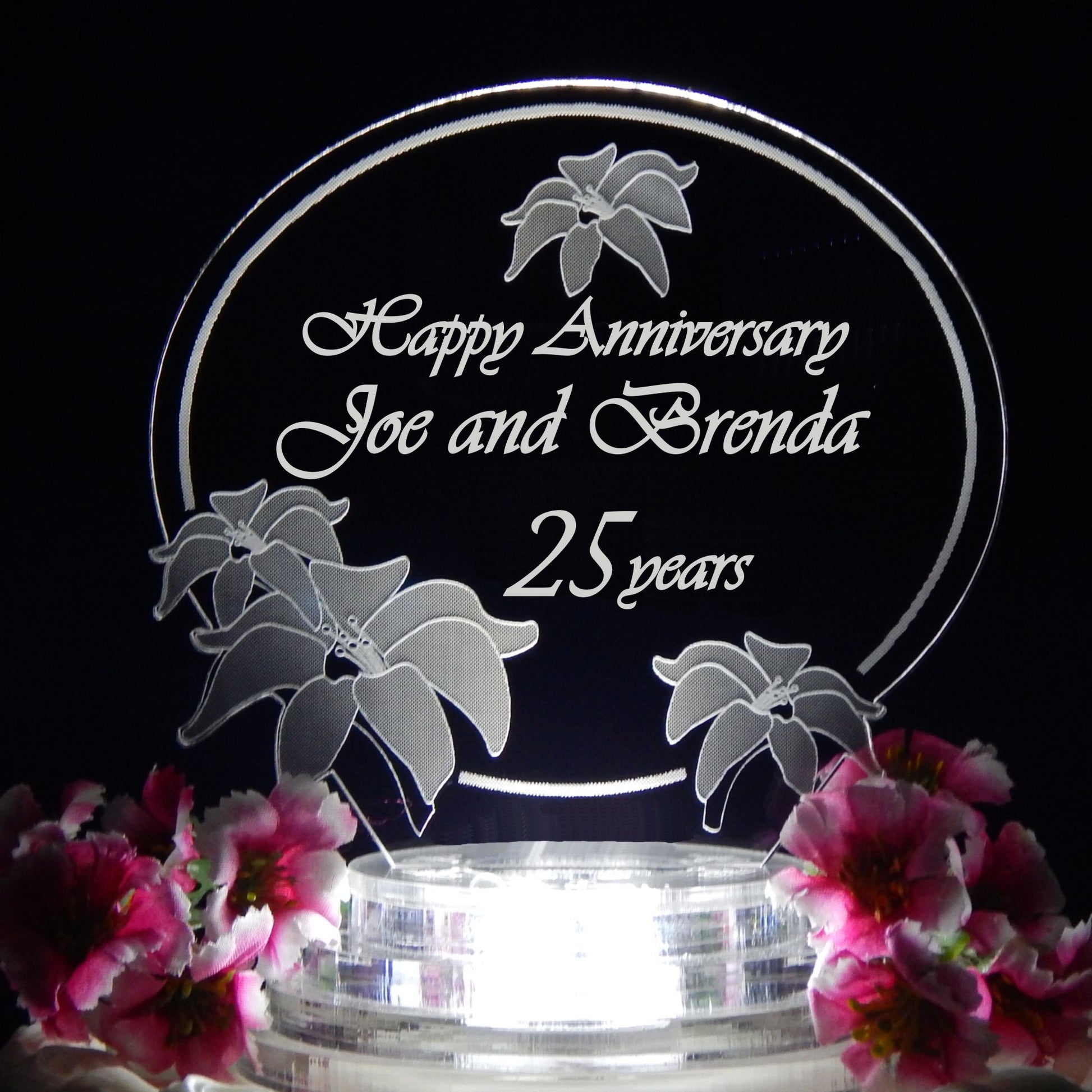 clear acrylic cake topper designed in a lily flower theme engraved with names and Happy Anniversary
