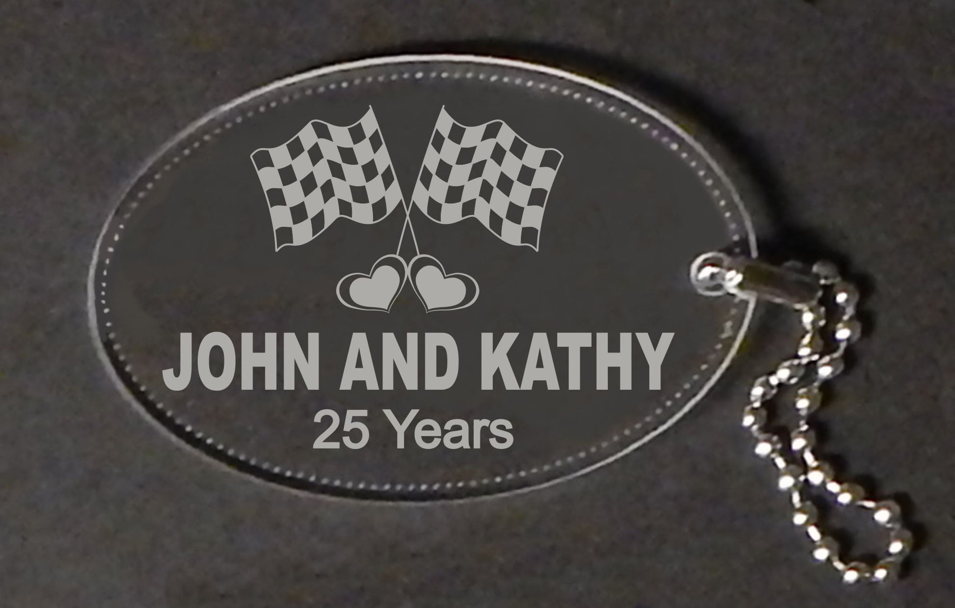 oval acrylic keychain designed with a set of racing flags along with names and anniversary years, with a small metal chain attached