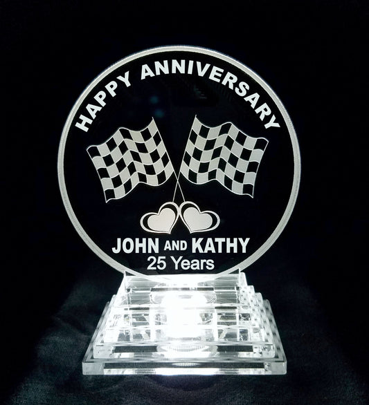 round acrylic cake topper designed with a set of racing flags and engraved with Happy Anniversary along with names and number of years married