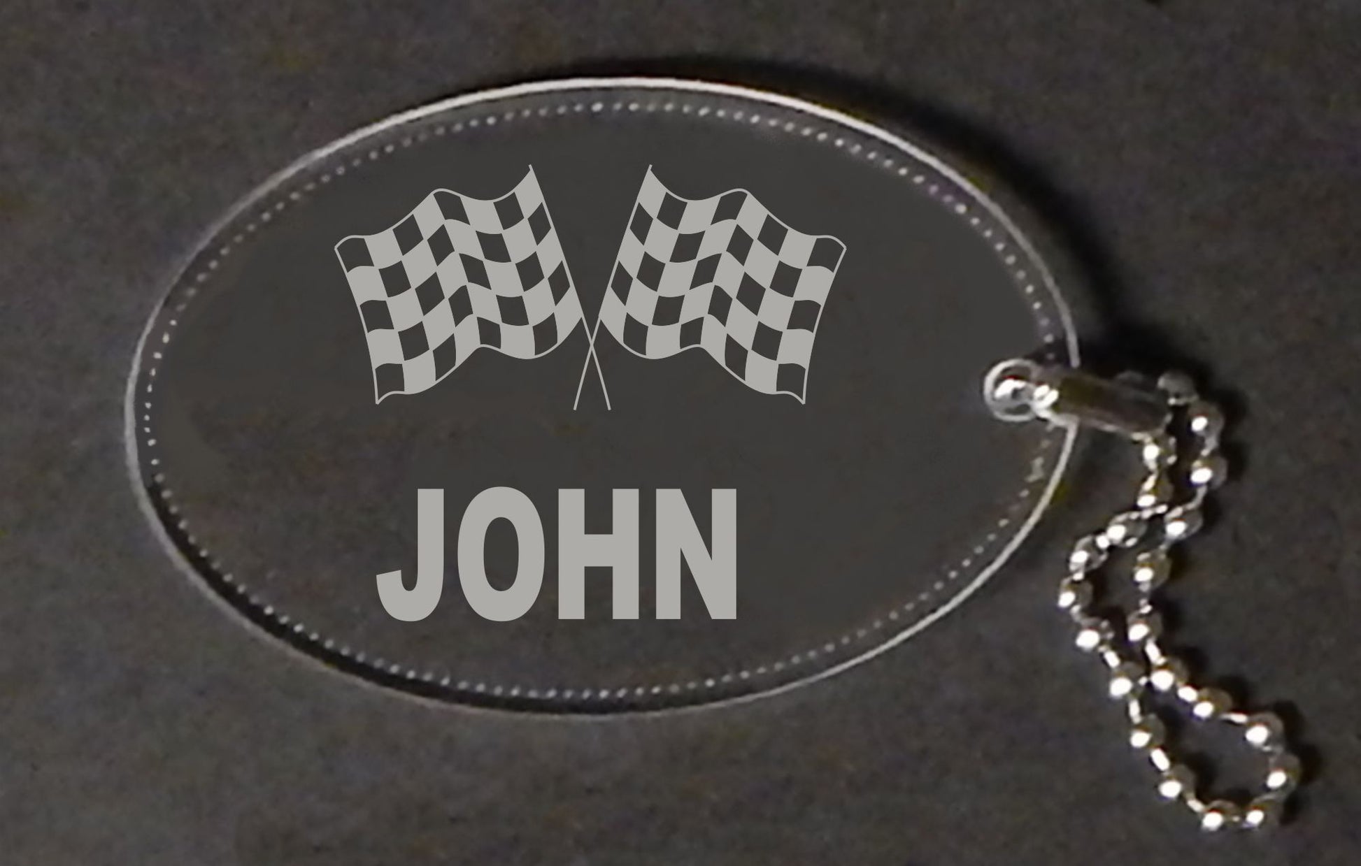 oval acrylic keychain with a set of racing flags and a name, with a small metal chain attached