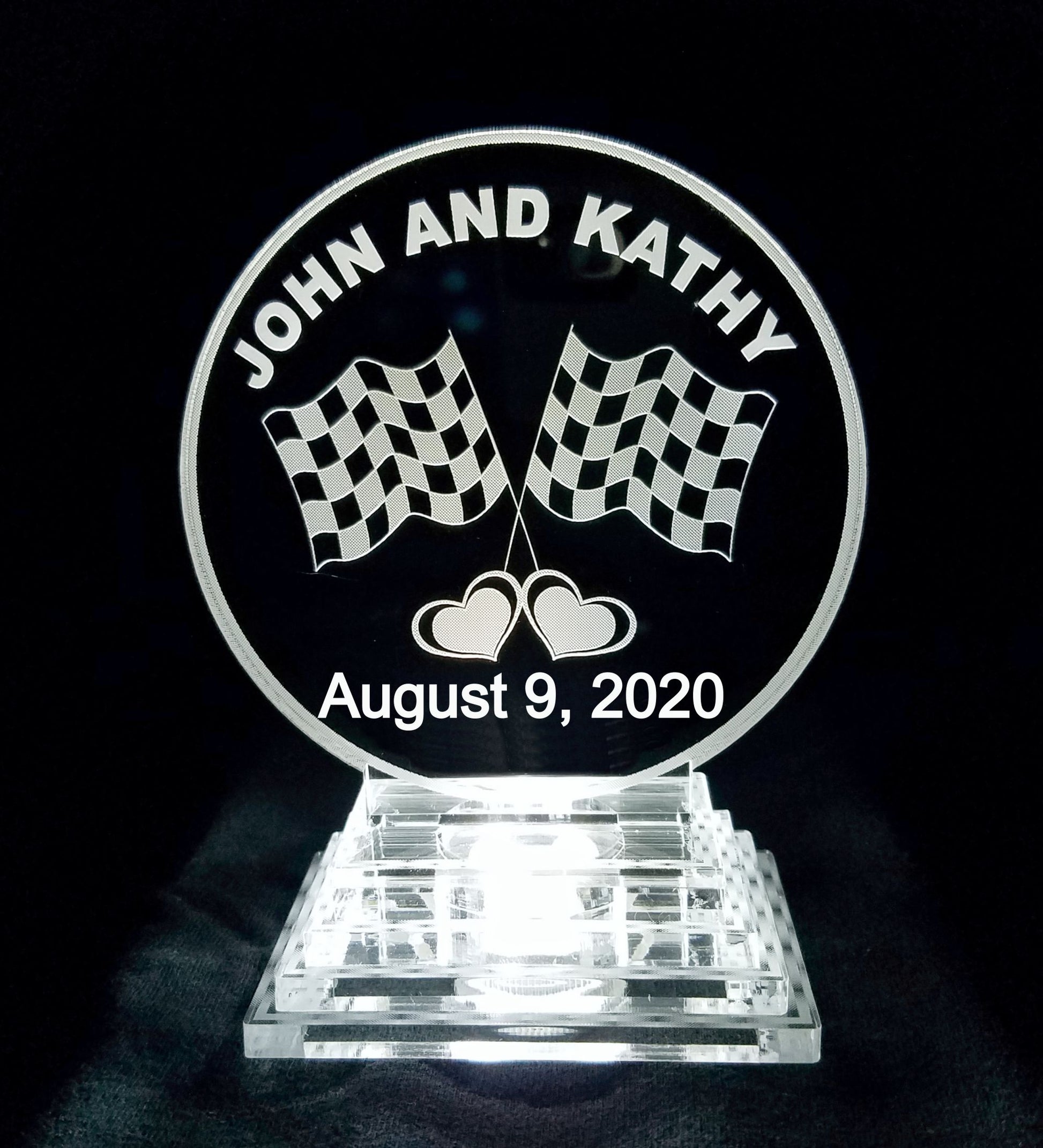 acrylic round cake topper decorated with a set of racing flags and engraved with names and date