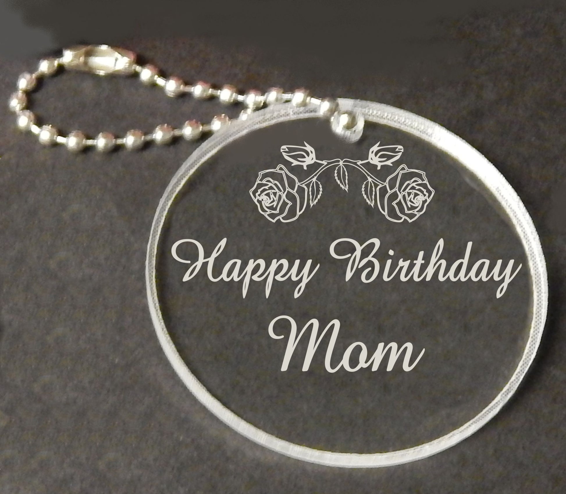 acrylic round keychain favor engraved with a rose design and attached to a small chain