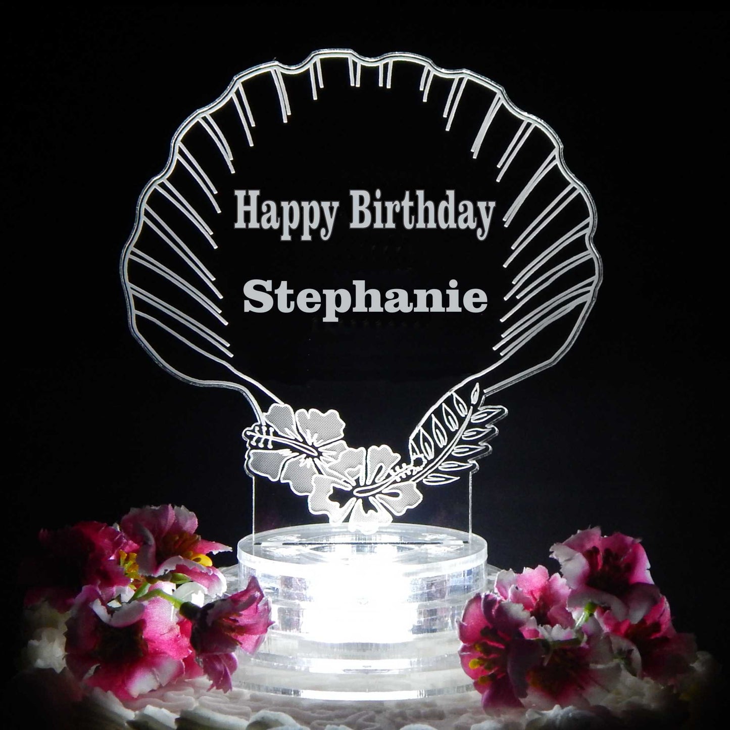 clear acrylic seashell shaped cake topper lighted with a white light and engraved with Happy Birthday and name