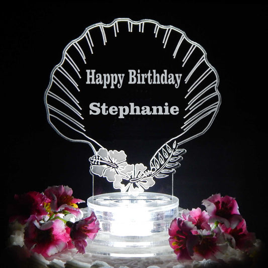 clear acrylic seashell shaped cake topper lighted with a white light and engraved with Happy Birthday and name