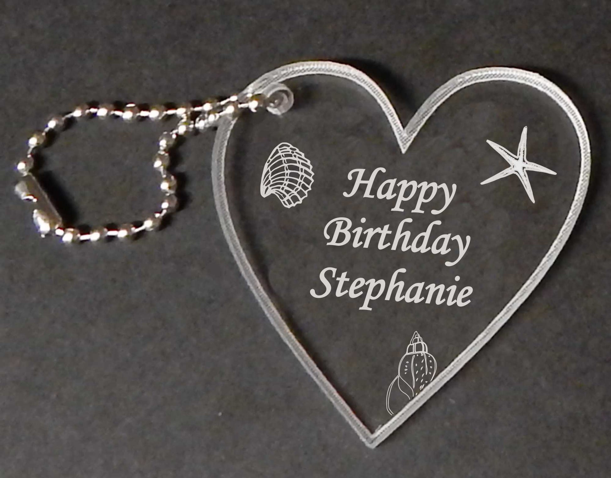heart shaped keychain designed with seashells and name and Happy Birthday, with a small metal chain attached