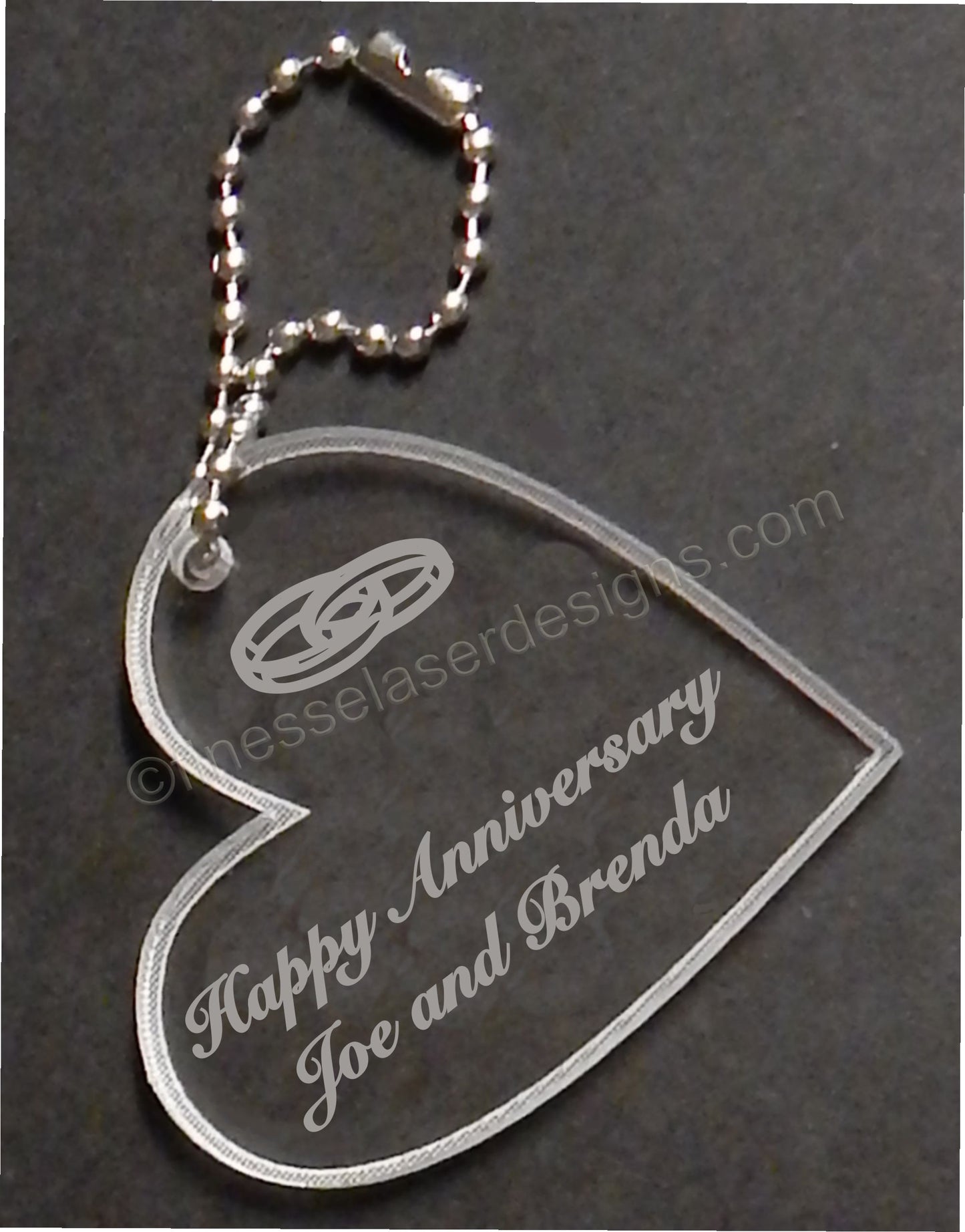 heart shaped keychain favor designed with wedding rings and engraved with Happy Anniversary and names, with small metal chain attached