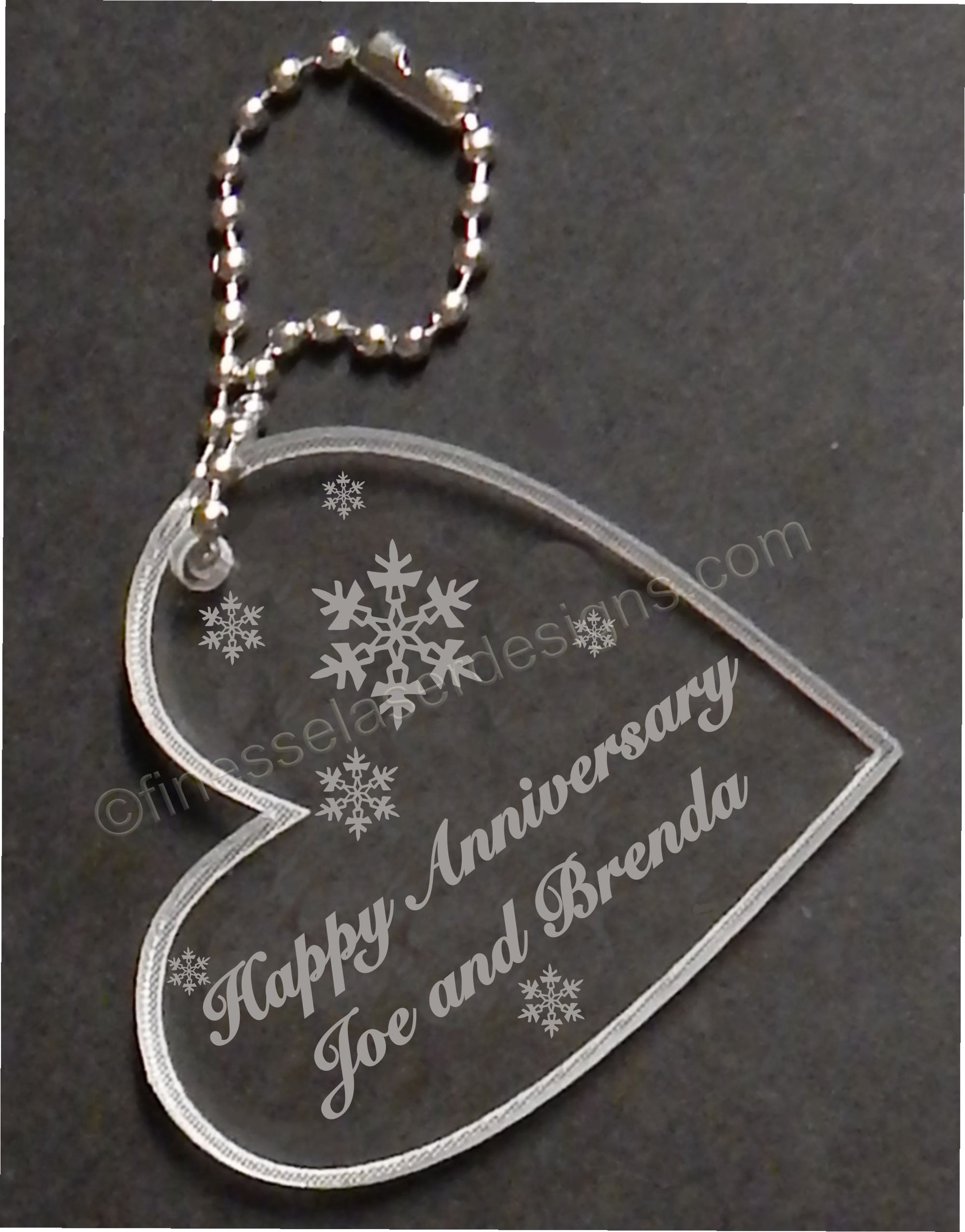 heart shaped keychain favor designed with wedding snowflakes and engraved with Happy Anniversary and names, with small metal chain attached