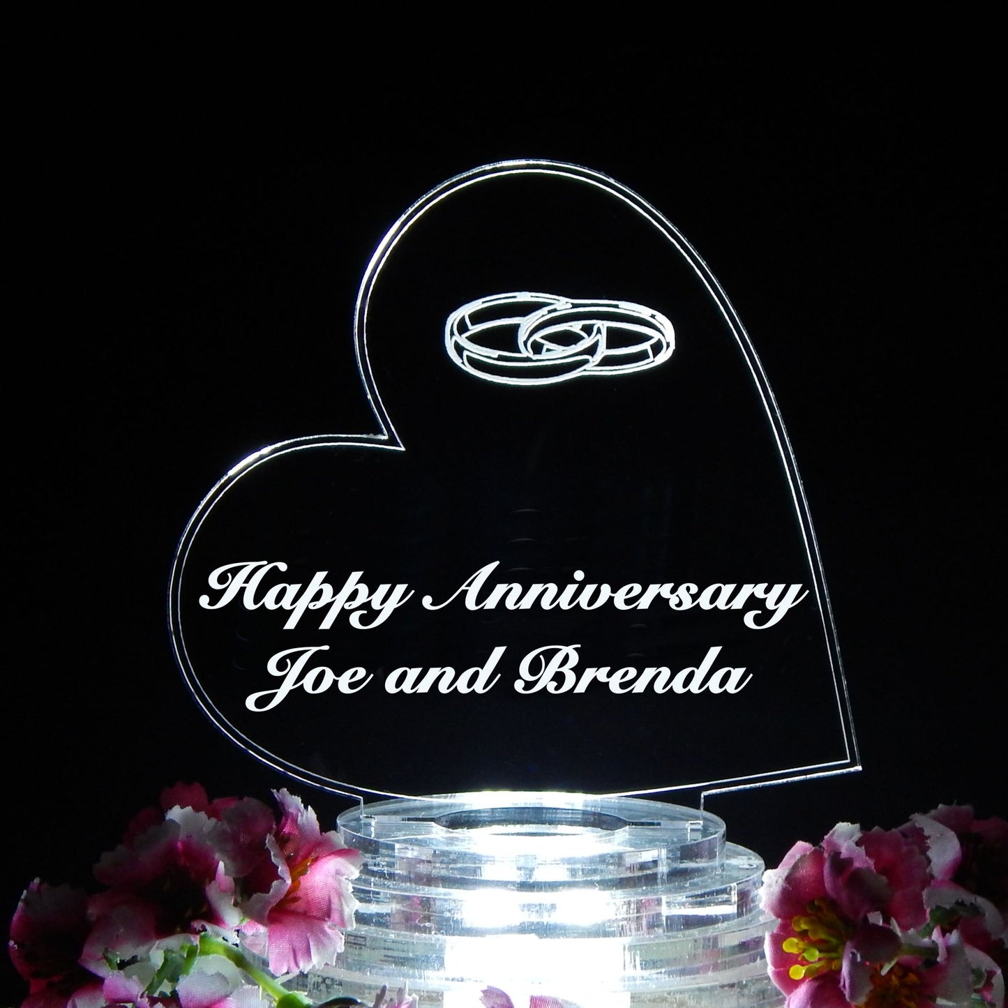 heart shaped acrylic cake topper designed with wedding rings and engraved with Happy Anniversary and names