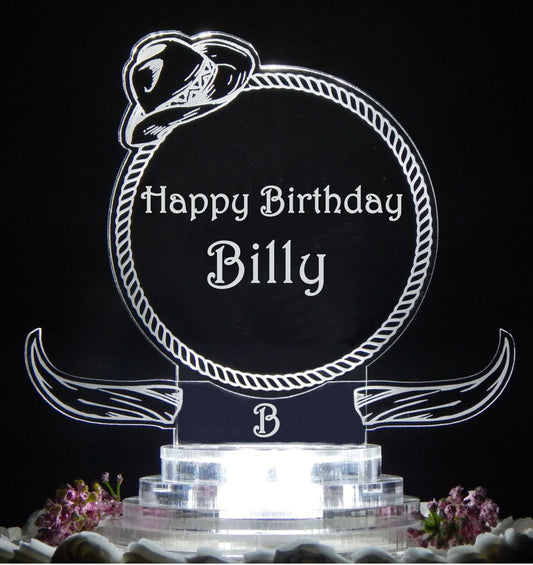 clear acrylic cake topper designed in a western cowboy theme with steer horns and cowboy hat, engraved with name and Happy Birthday