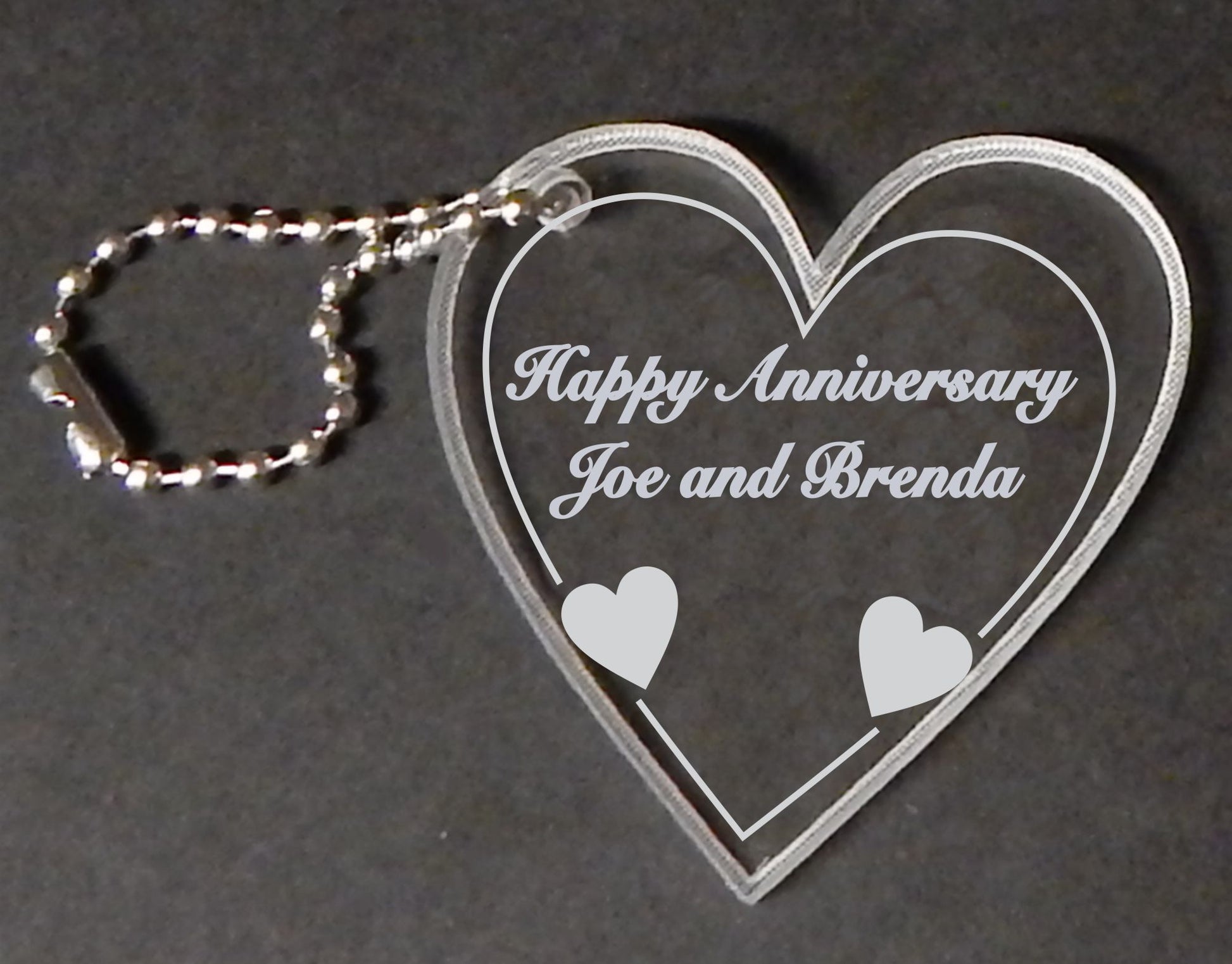 heart shaped acrylic keychain with small attached chain, engraved with Happy Anniversary and names