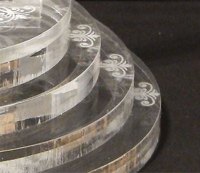 partial view of an acrylic round tiered base for a cake topper with a pretty design on each tier