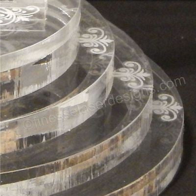 partial view of an acrylic round tiered base for a cake topper with a pretty design on each tier