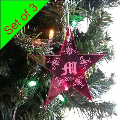 acrylic red star shaped ornament hanging on a tree limb with a monogrammed letter M in the center of the ornament