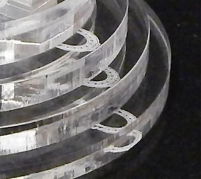 partial view of an acrylic round tiered base for a cake topper with a horseshoe design on each tier