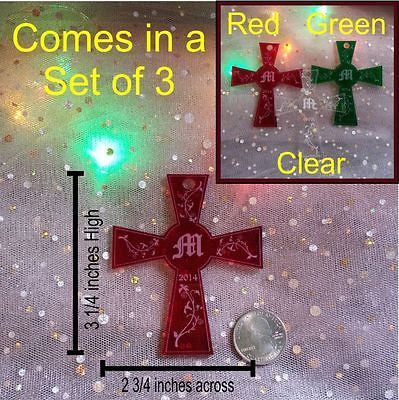 view of a red cross shaped ornament next to a quarter to show dimentions, and a small insert box showing clear, green and red cross ornaments in the upper right corner