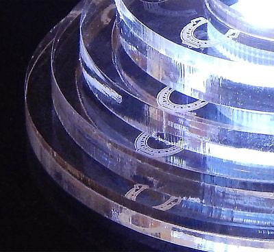 partial view of an acrylic round tiered base for a cake topper with a horseshoe on each tier