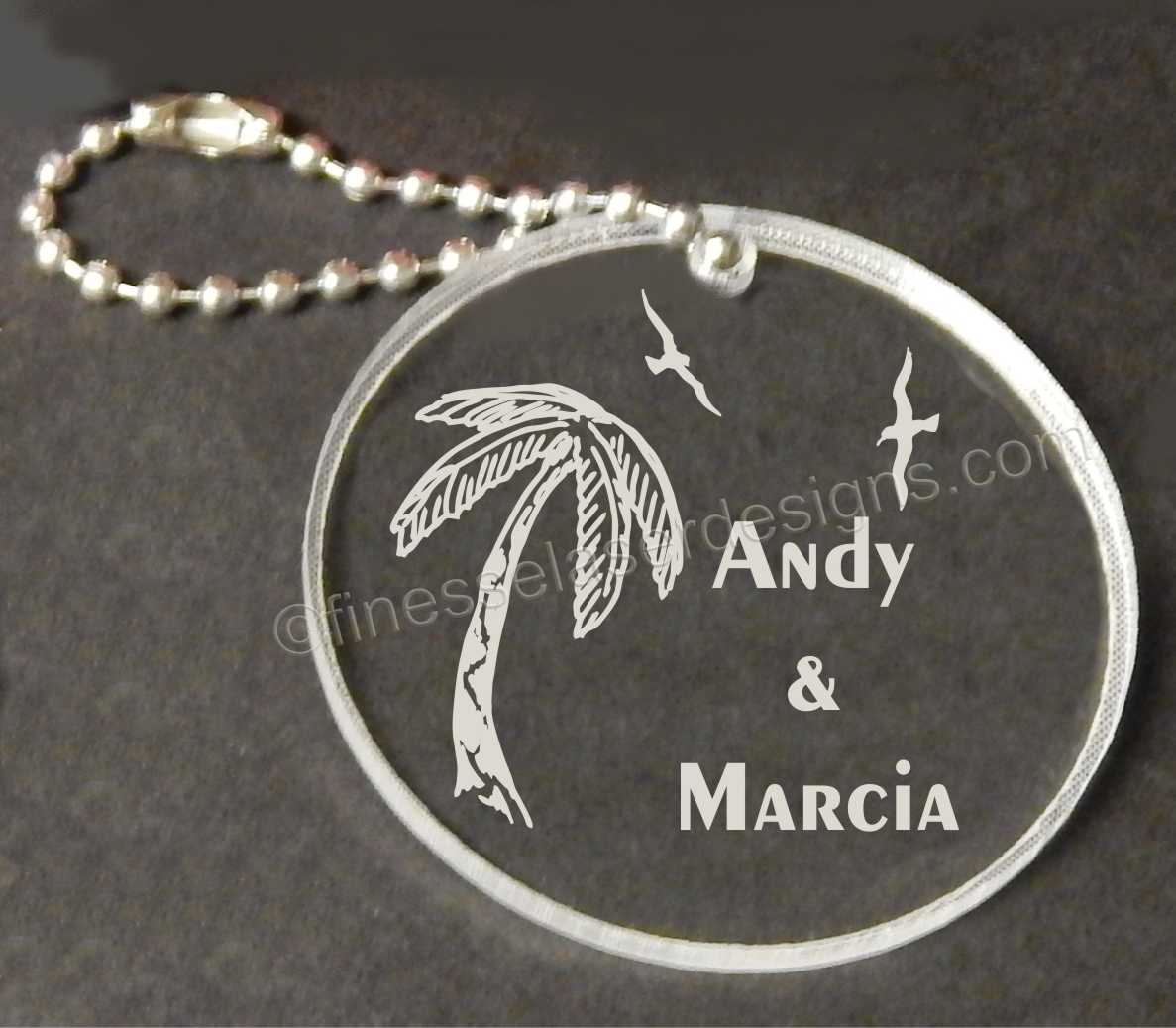 round acrylic keychain designed with palm tree, seagulls and names with a small metal chain attached