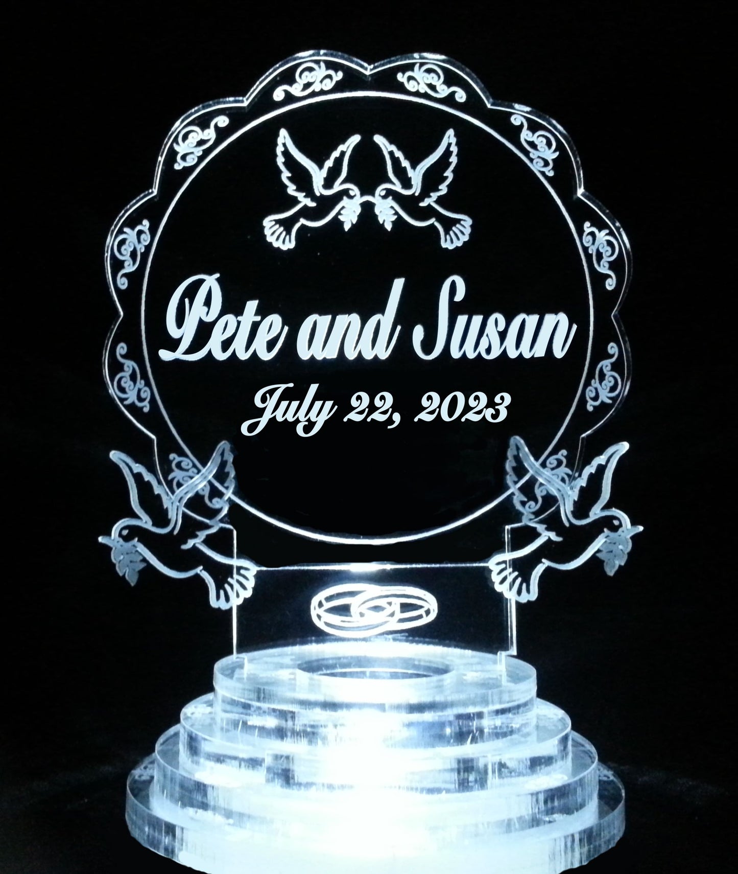 Acrylic lighted cake topper with a dove design and wedding rings, along with names and date