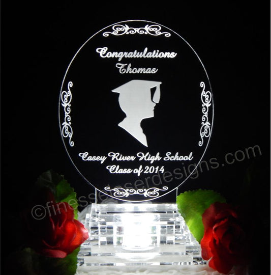 acrylic oval shaped graduation cake top with a boy silhouette engraved along with name, school and year
