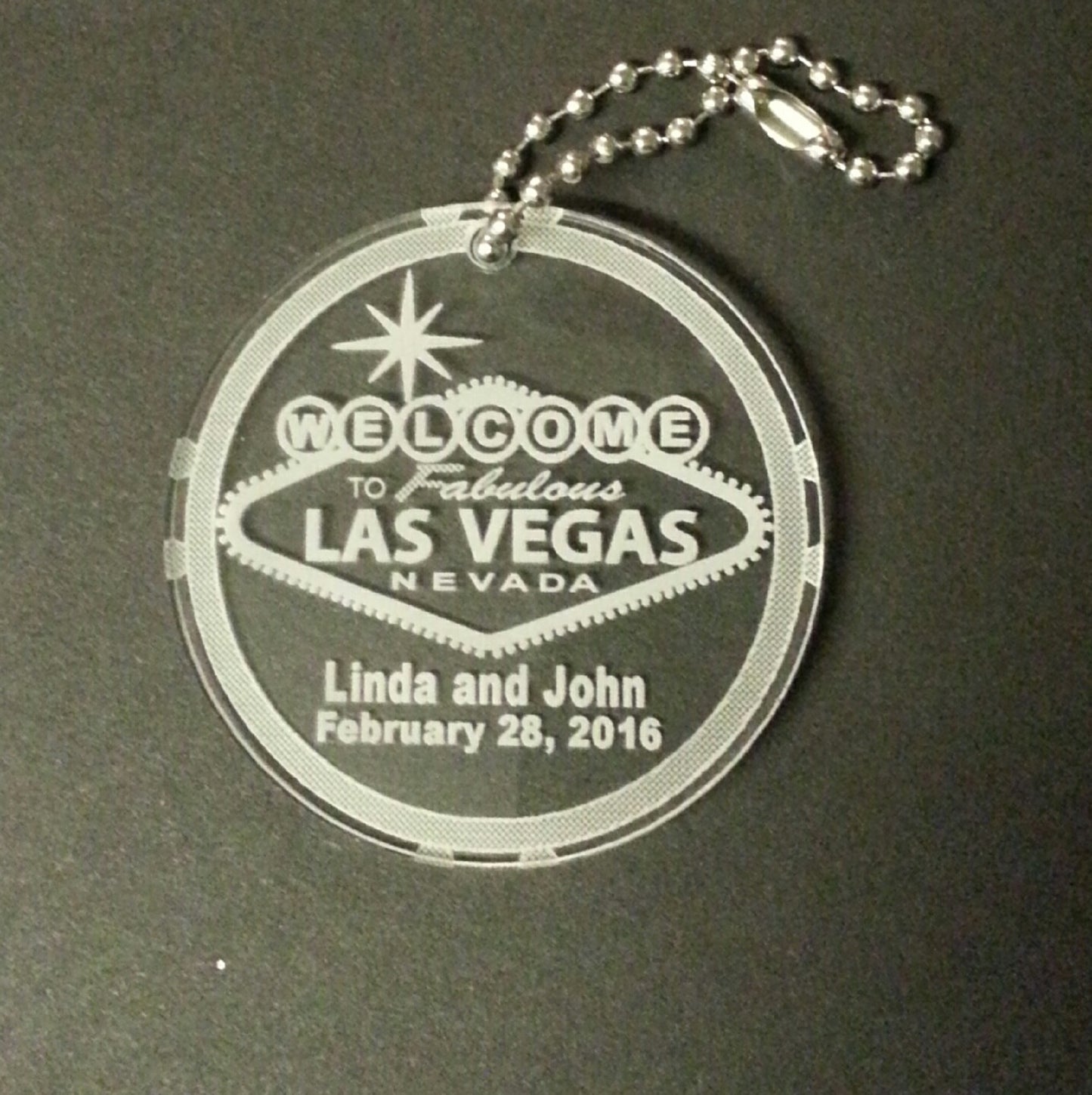 round acrylic keychain with a Welcome to Las Vegas sign along with names and date with a small metal chain attached