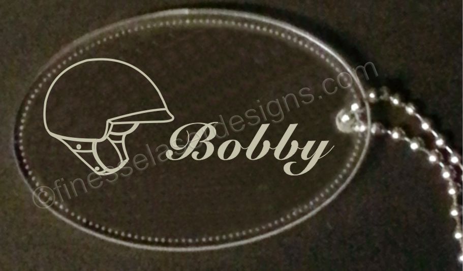 oval acrylic keychain with helmet and name engraved and a small metal chain attached