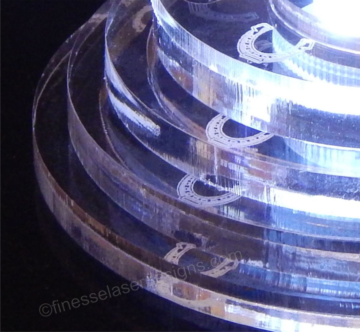 partial view of an acrylic round tiered base for a cake topper with a horseshoe design on each tier