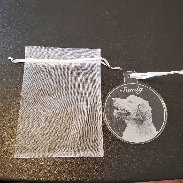 mesh bag next to an acrylic round ornament engraved with a pet photo and name